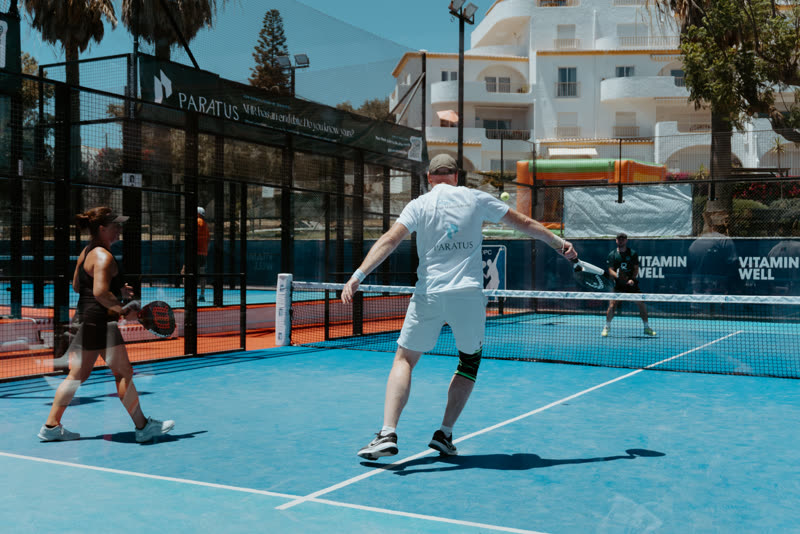 Dean Arden of Paratus Wealth playing a volley at the net during the Luz Padel Masters in the Algarve, in front of a Paratus branded court